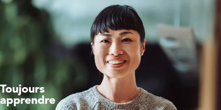 Portrait d’une femme souriante avec un fond flou et le texte "Toujours apprendre" en blanc.